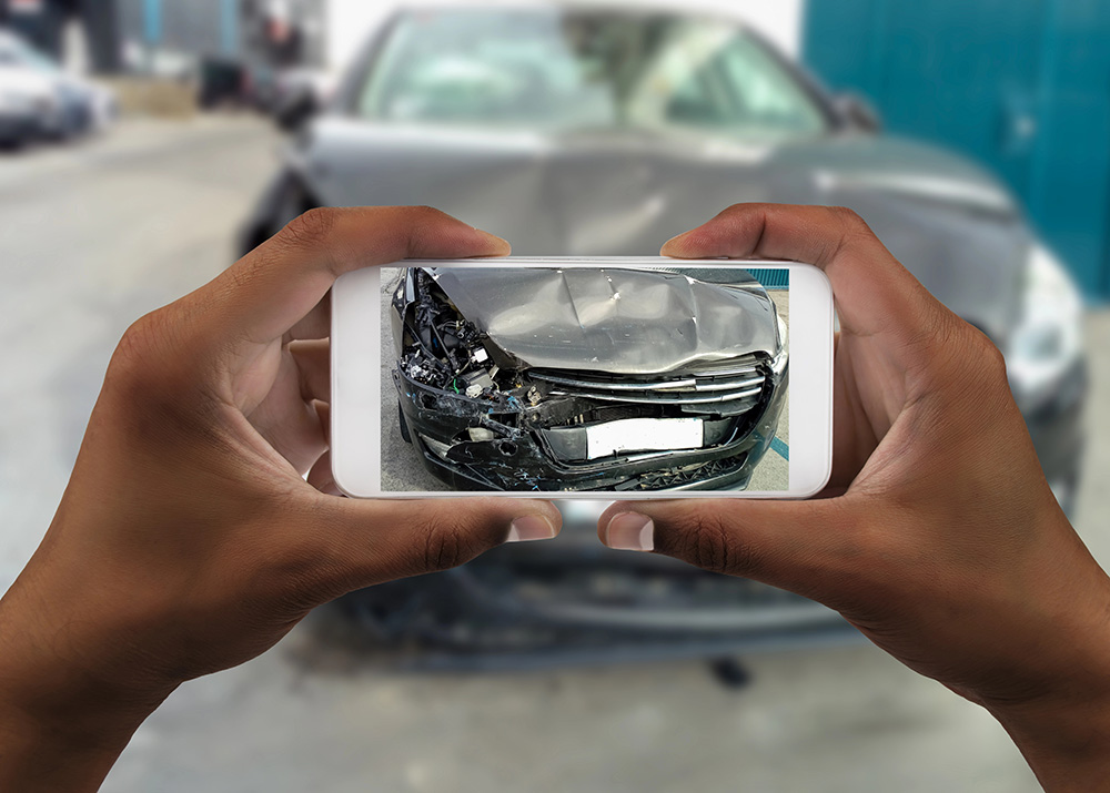 Man photographing his car with damages