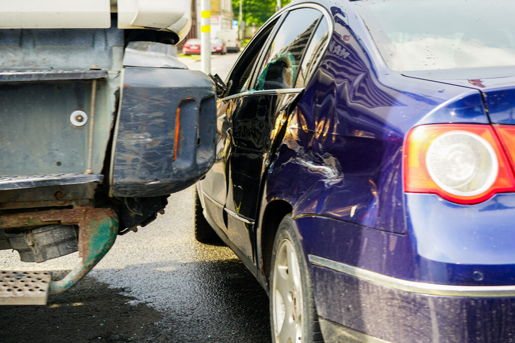 Traffic accident showing a car with major side damage after collision with a truck in city